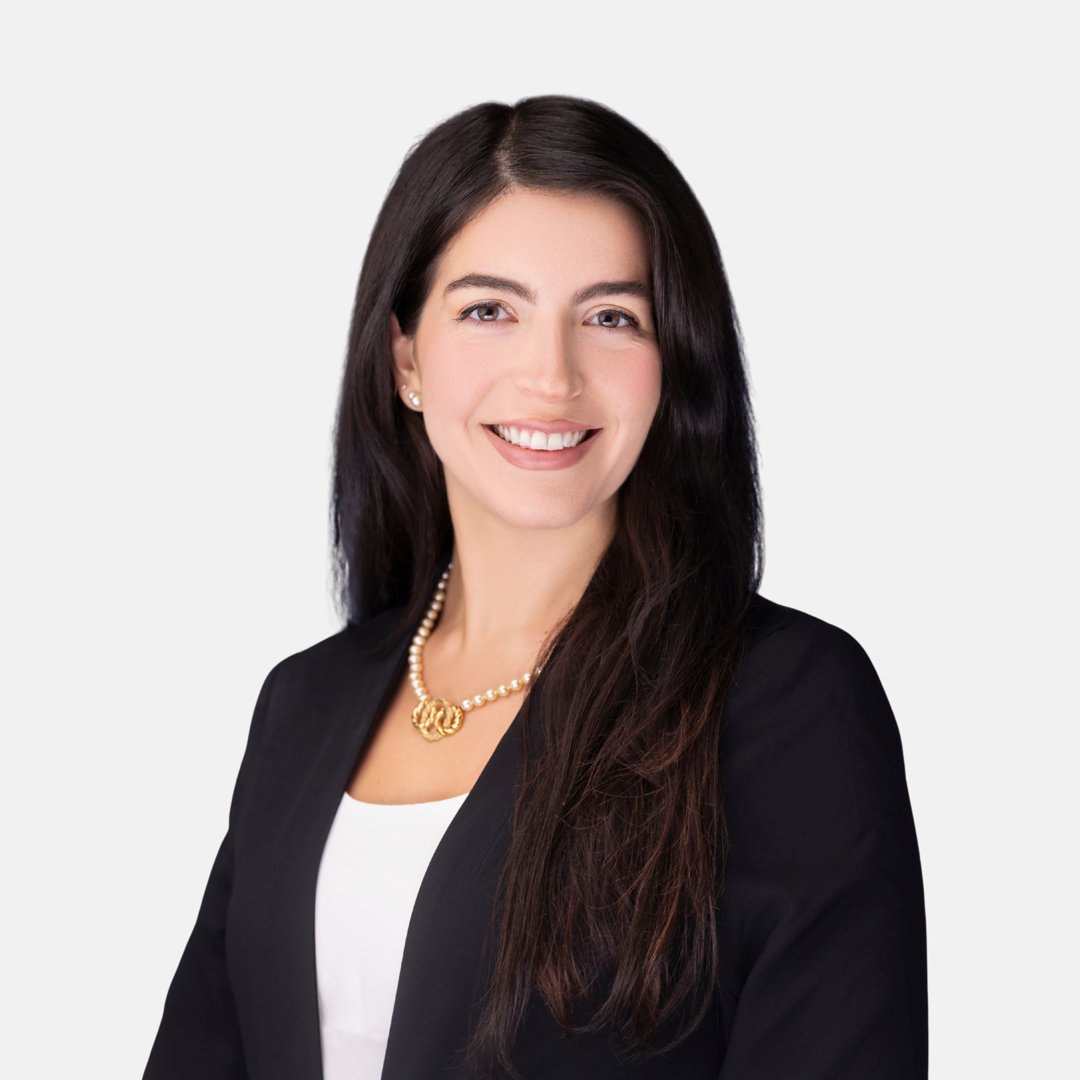 Headshot of Andrea V. Martinez with long dark hair, wearing a dark blazer, white top, and gold necklace, smiling against a light background