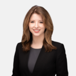 Headshot of Anna Schaffner with brown hair and a dark blazer smiling against a light background