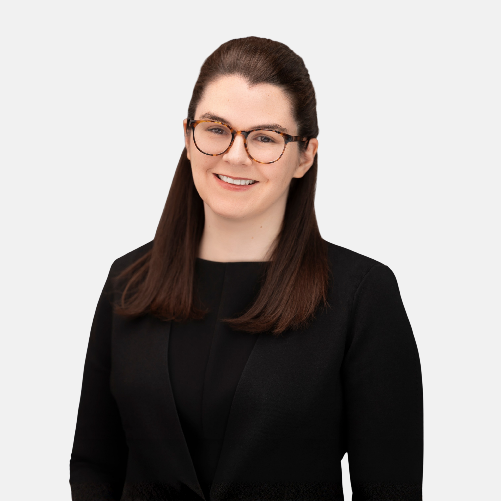 Headshot of Augusta Nau with dark hair and glasses, wearing a dark blazer and smiling against a light background
