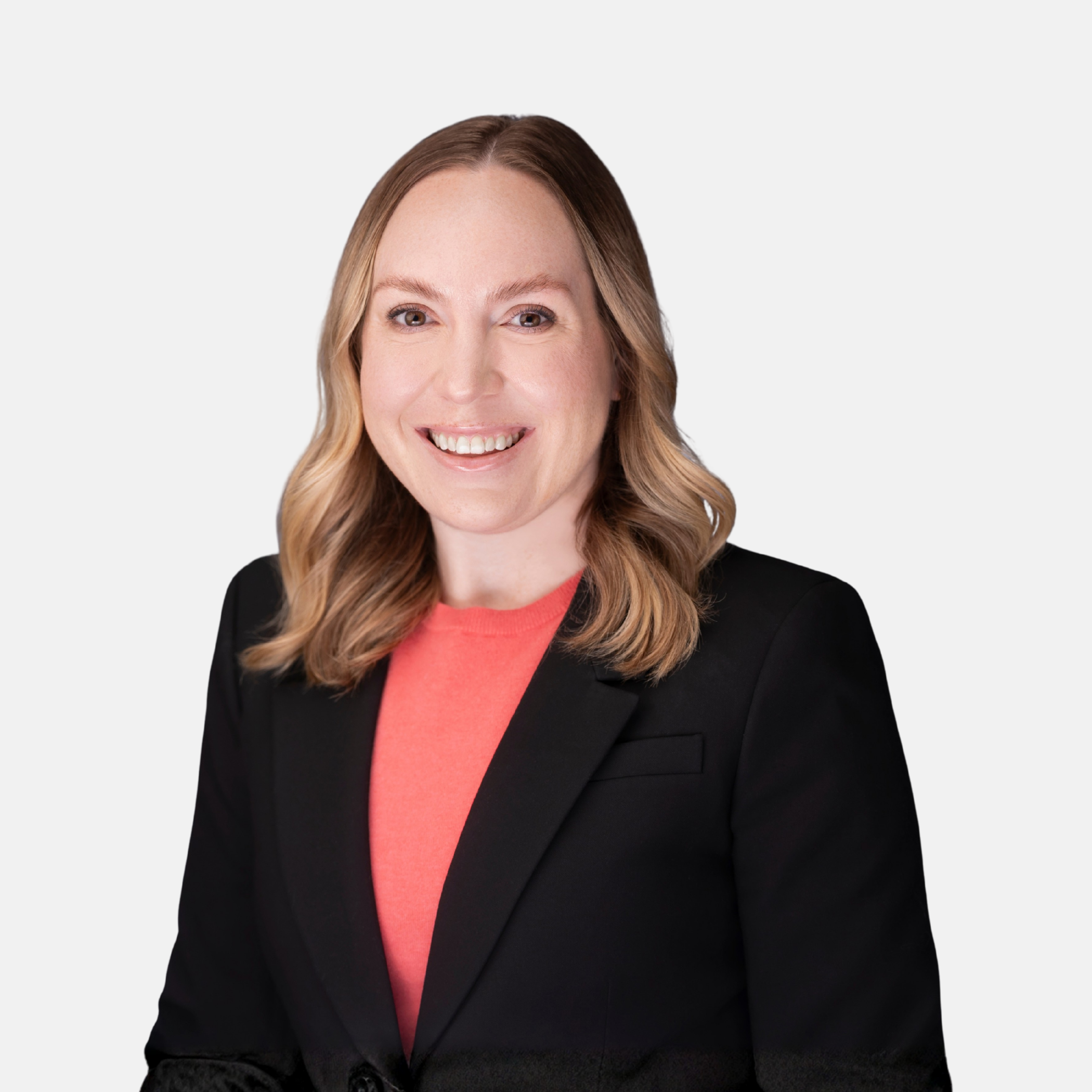 Headshot of Megan Hovious with shoulder-length blonde hair, wearing a dark blazer and coral top, smiling against a light background